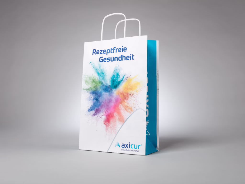 Weiße Papiertragetasche mit Umschlag und gedrehter Papierkordel für axicur – bedruckt von Paolo Sandro