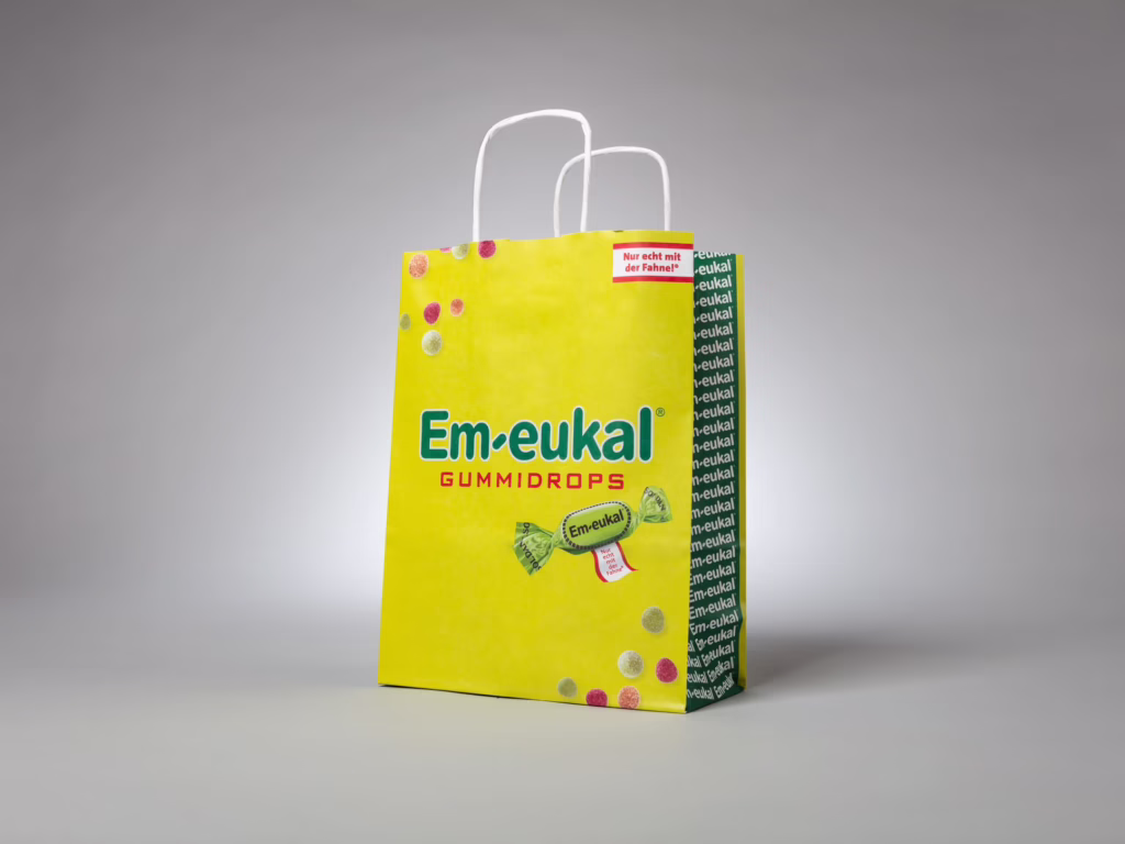 Gelbe Papiertragetasche mit gedrehter Papierkordel für Em-eukal Gummidrops – bedruckt von Paolo Sandro